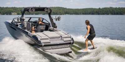 Unbranded inboard wake boat towing an adult wakesurfer on a lake
